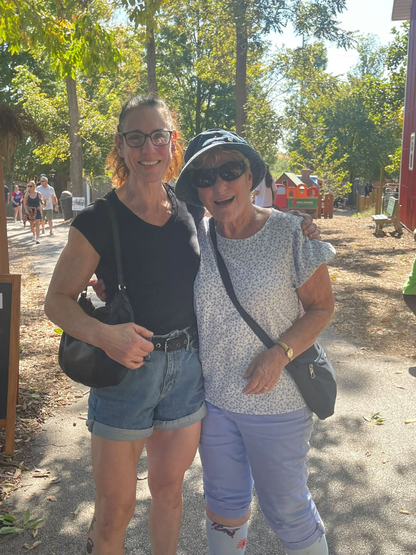 Two Xi Chapter members smiling together on a sunny path at Curtis Orchard